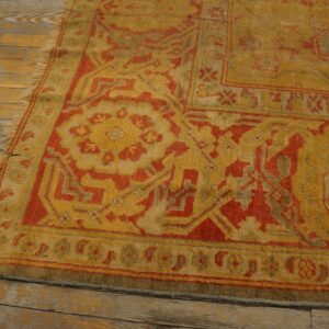 Gold and red patterned shag rug with fringes resting on distressed, light wood flooring.