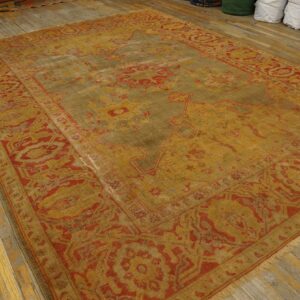 Distressed traditional rug in faded gold and red tones covers worn wood floor planks.