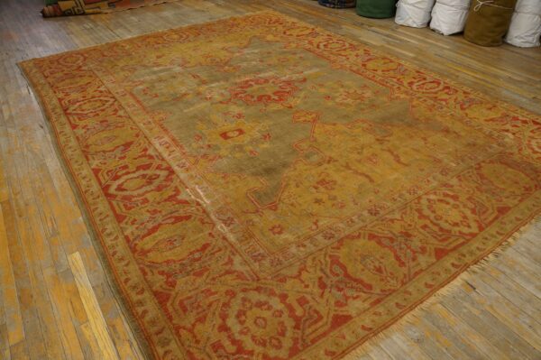 Distressed traditional rug in faded gold and red tones covers worn wood floor planks.