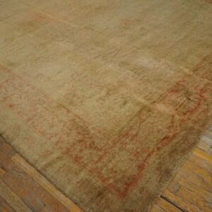 A large, faded green and reddish-pink area rug covers distressed hardwood flooring.