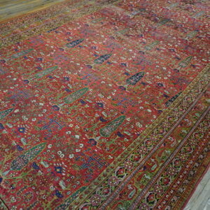 Large distressed red rug featuring dense traditional botanical patterns and elaborate borders on gray wood flooring.
