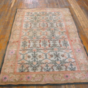Traditional beige and pink rug with a floral trellis pattern lying on wide plank hardwood flooring.
