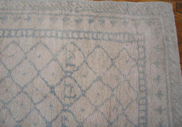 A shaggy cream rug with a light blue diamond pattern lies on a wooden floor.