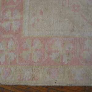 A cream and rose border pattern is visible on a textured pile rug resting on wood planks.