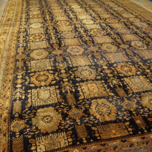 Ornate dark and gold area rug with repeating medallions displayed on light wood plank flooring.