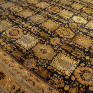 Low-pile rug featuring dense geometric patterns in black, rich gold, and muted teal on wood flooring.