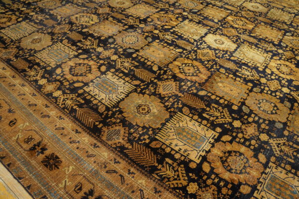 Low-pile rug featuring dense geometric patterns in black, rich gold, and muted teal on wood flooring.