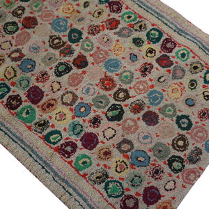 High-pile gray rug featuring a dense pattern of multicolored circular motifs and striped flatwoven edges.