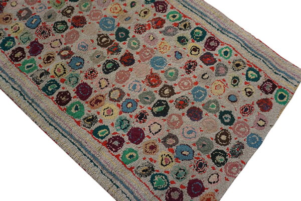 High-pile gray rug featuring a dense pattern of multicolored circular motifs and striped flatwoven edges.