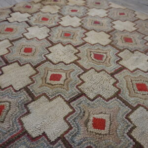 Shaggy rug showing repeating cream, red, blue, and brown geometric star patterns on a wood floor.