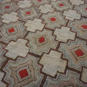 Nubby, low-pile rug featuring interlocking geometric patterns in cream, red, brown, and blue.