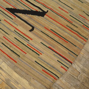 Textured beige rug with short red, gray, and dark green stripes, featuring a large black angular shape on wood planks.