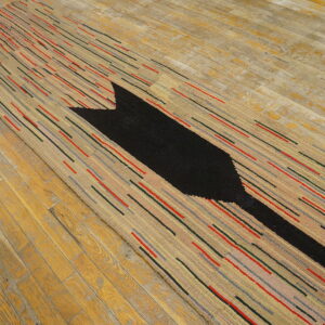 Textured runner rug with beige ground, multicolored dash stripes, and a large black arrow on wood.
