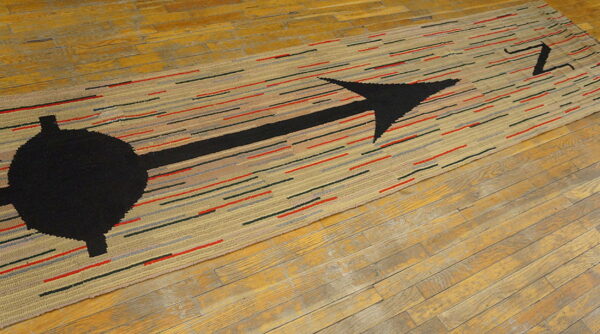 Textured beige runner rug featuring a bold black arrow and colorful dashes on a plank wooden floor.