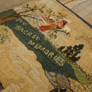 Textured, looped rug showing yellow, green, and red scenic pattern with text on rustic wood planks.