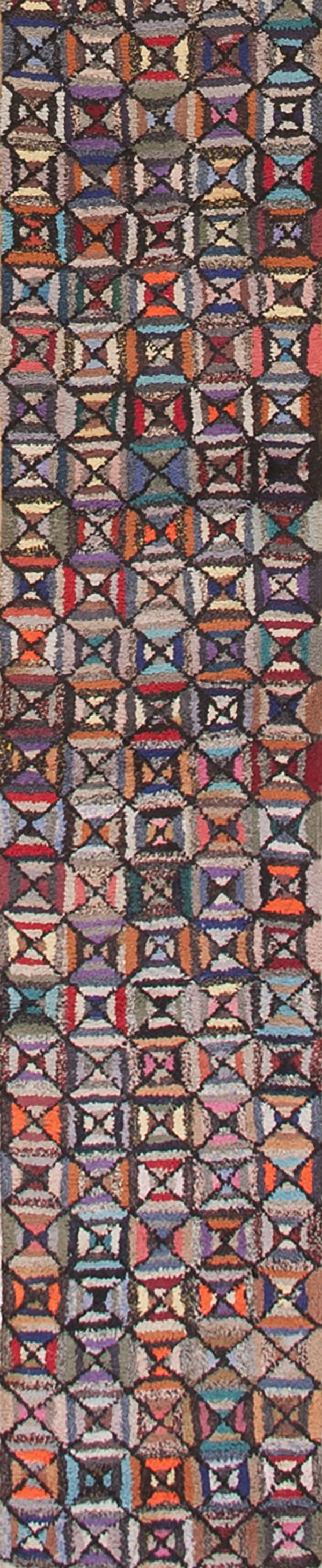 Textured, multicolor runner rug displaying repeating geometric hourglass motifs in shades of red, blue, orange, and purple.