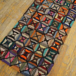 Textured, high-pile multicolor runner rug with a patchwork triangular pattern lies on distressed yellow wood floor.