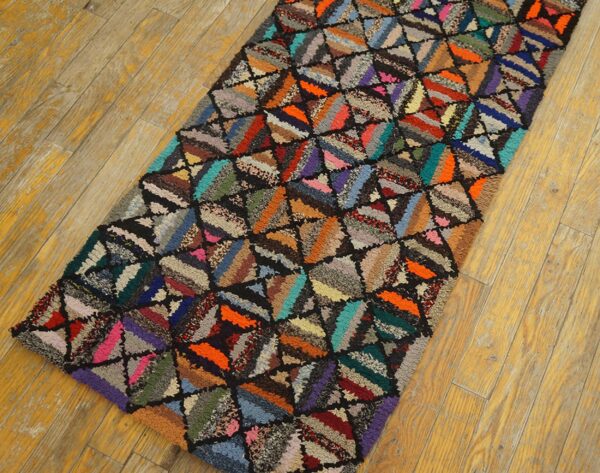 Textured, high-pile multicolor runner rug with a patchwork triangular pattern lies on distressed yellow wood floor.