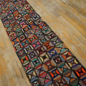 Shaggy, multicolored geometric runner rug laid diagonally on distressed light wood flooring.