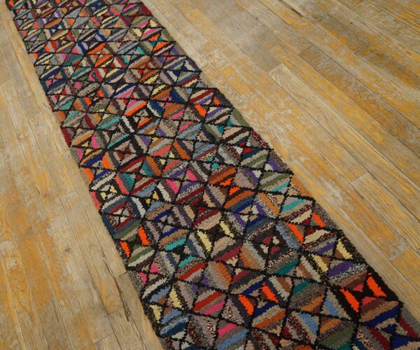 Shaggy, multicolored geometric runner rug laid diagonally on distressed light wood flooring.