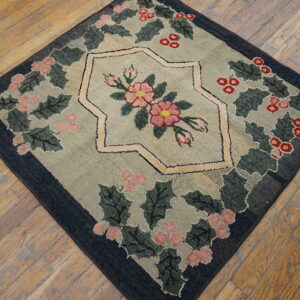 Low-pile square rug displaying a pink and red floral design framed by green leaves on rustic wood floors.