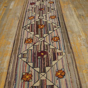 Textured runner rug with striped background, geometric diamonds, and flowers rests on a worn wood floor.