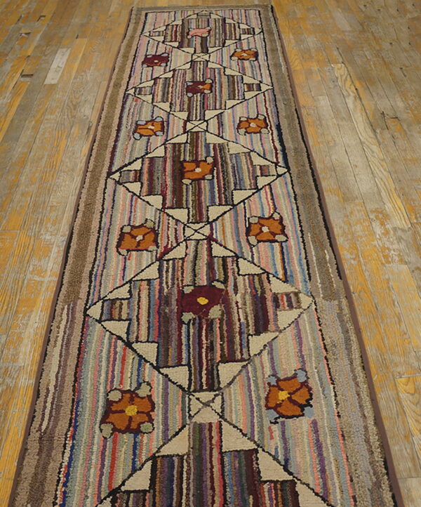 Textured runner rug with striped background, geometric diamonds, and flowers rests on a worn wood floor.