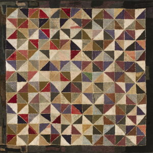 A high-texture rug featuring a patchwork geometric pattern of multicolored triangles and a black outer border.