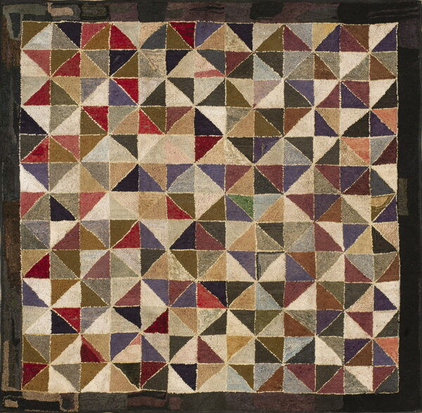 A high-texture rug featuring a patchwork geometric pattern of multicolored triangles and a black outer border.