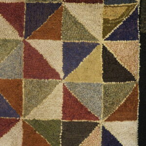 Close up of a hooked rug featuring multicolored geometric triangles and a solid black border.