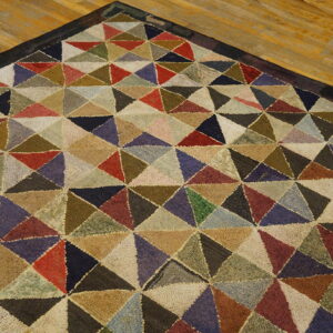 Textured rug corner displaying a multicolored geometric triangle pattern sits on light hardwood planks.