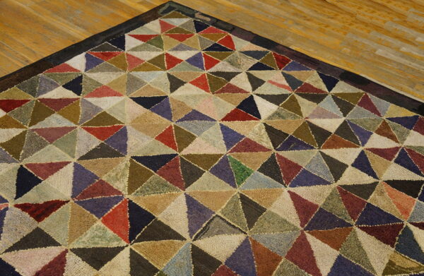 Textured rug corner displaying a multicolored geometric triangle pattern sits on light hardwood planks.