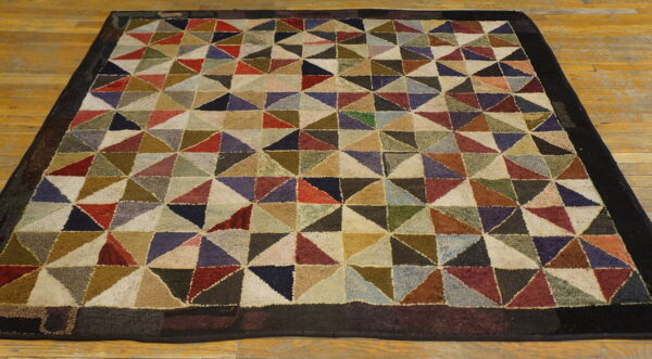 Multicolor geometric rug featuring varied triangular blocks, a dark border, and a chunky pile texture on wood flooring.