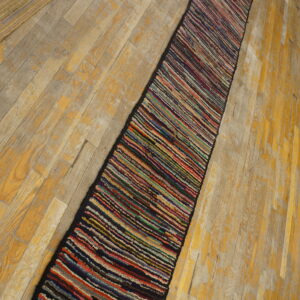 A highly textured, multi-colored striped runner rests diagonally on distressed light wood floors.
