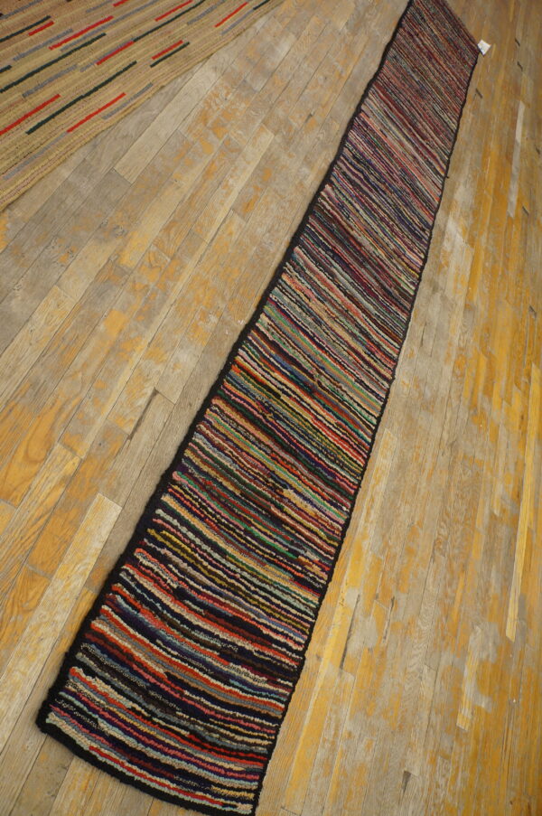 A highly textured, multi-colored striped runner rests diagonally on distressed light wood floors.