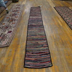 Three runners—one multicolored striped, one geometric, and one diamond-patterned—laid on worn hardwood flooring.