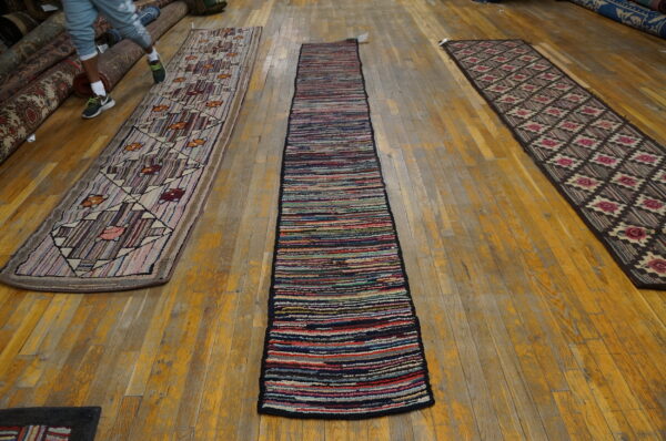 Three runners—one multicolored striped, one geometric, and one diamond-patterned—laid on worn hardwood flooring.