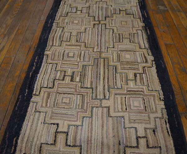 Geometric runner rug featuring beige loops, brown, and blue accents on distressed hardwood planks.