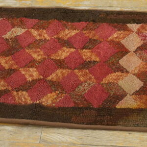 Textured runner rug with a tumbling diamond pattern in mixed reds, rust, and tan, framed by dark brown.