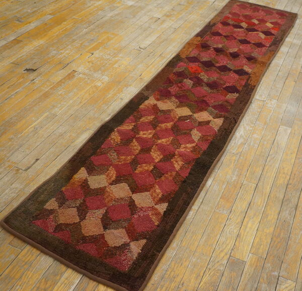 Textured runner rug featuring a maroon and beige cube pattern on distressed wooden planks.