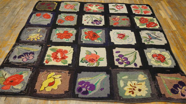 A dark-bordered quilt-style rug with multicolored floral and bird squares resting on light wood floors.