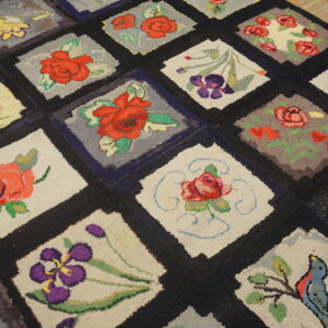 A thick, multicolored floral hooked rug featuring a diamond grid pattern resting on light wood floors.