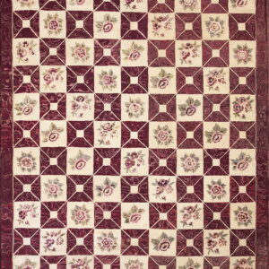 A textured rug in cream and deep maroon with a repeating geometric grid and small floral motifs.
