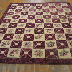 Burgundy and cream checkered rug featuring floral motifs rests on light wood floors.