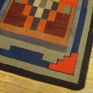 Geometric loop pile rug in warm rust, blue, green, and orange blocks bordered in black on wooden flooring.
