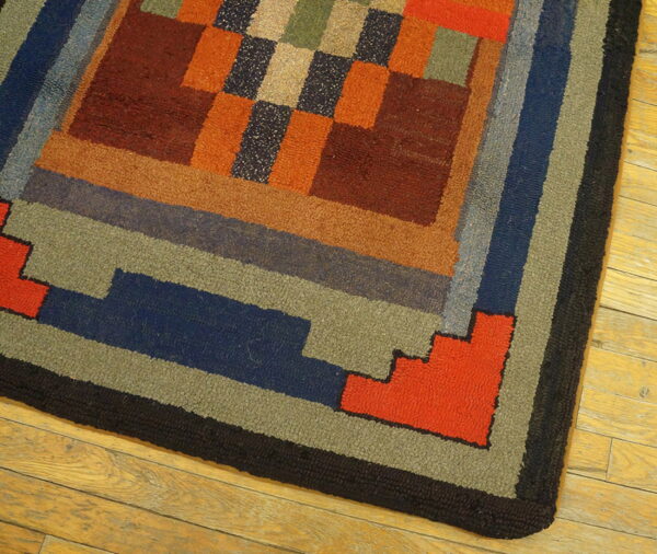 Geometric loop pile rug in warm rust, blue, green, and orange blocks bordered in black on wooden flooring.