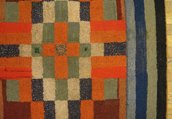 High-pile, multi-colored rug with checkerboard patterning and vertical stripes rests on wood flooring.