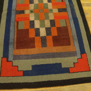 Multicolor rug with a textured pile, featuring a checkerboard center and thick step-design borders on wood floors.