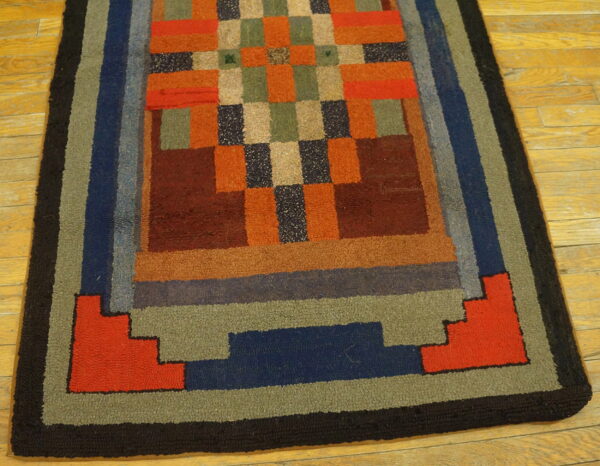 Multicolor rug with a textured pile, featuring a checkerboard center and thick step-design borders on wood floors.