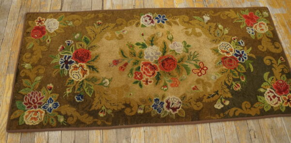 A plush runner rug with multicolored floral designs on an olive and brown ground, placed on wood floorboards.